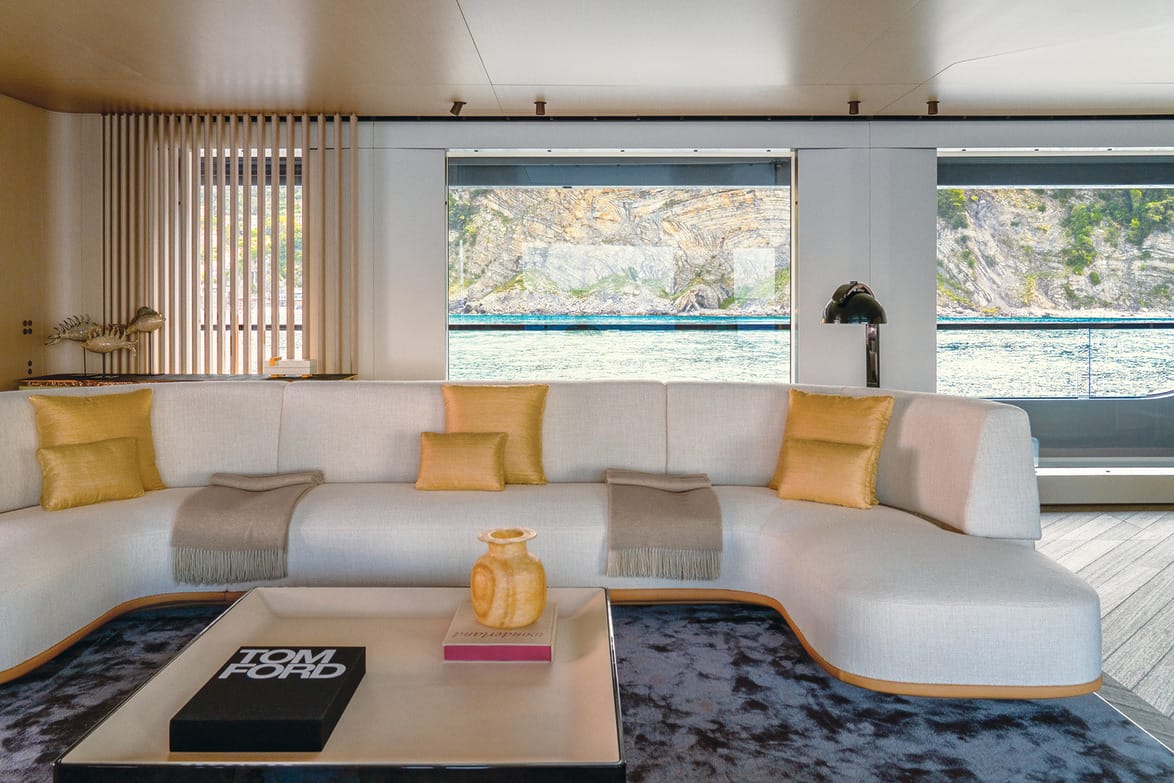 luxurious yacht interior with white sectional sofa, yellow cushions, modern decor, large windows offering scenic ocean views