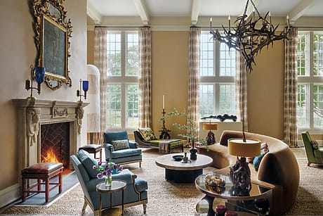 Spacious living room with a fireplace, large windows, elegant furniture, and a unique chandelier.