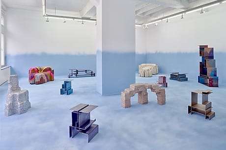 Modern art gallery with abstract sculptures on blue gradient floor and walls, featuring geometric and organic shapes.