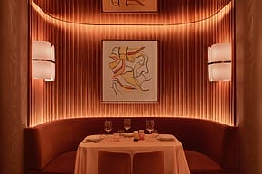 Cozy dining nook with a round table set for two, illuminated by warm ambient lighting and modern wall art.