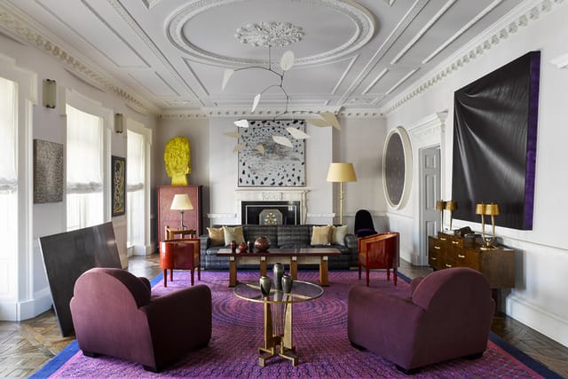 Elegant living room with purple chairs, modern art, ornate ceiling, and a vibrant purple rug.