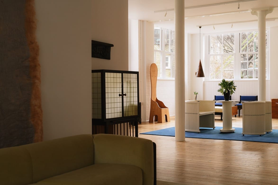 Modern living room with large windows, natural light, minimalist furniture, and a blue rug.