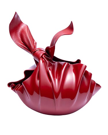 Red sculptural handbag with a glossy, folded design and a knotted handle, resembling a modern art piece.