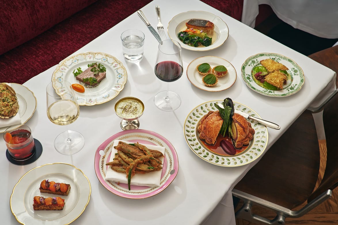 A variety of elegantly plated gourmet dishes on a restaurant table, accompanied by glasses of red and white wine.