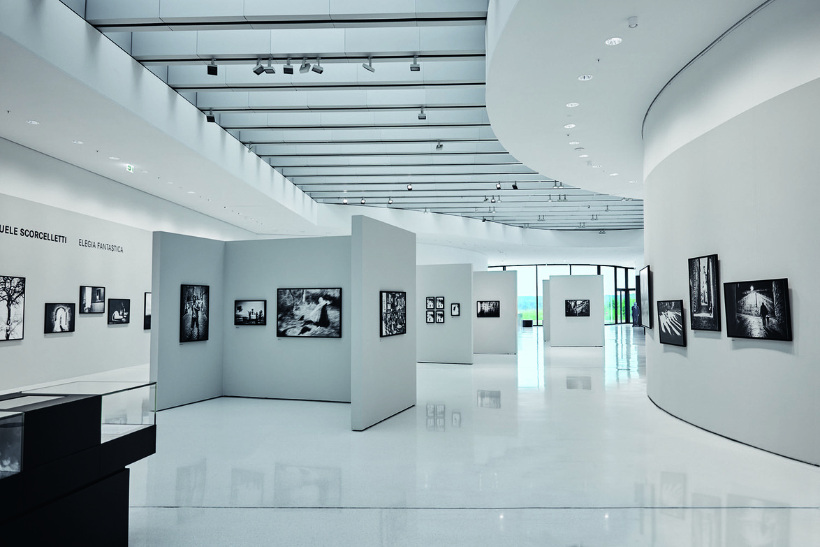 Modern art gallery with black and white photographs displayed on curved white walls and minimalistic interior design.