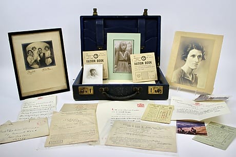 Vintage suitcase with family photos, ration books, letters, and documents displayed, evoking historical memories and nostalgia.