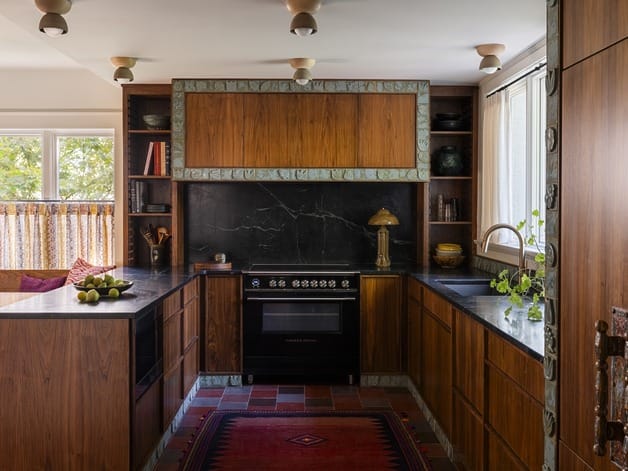 vintage kitchen with wooden cabinets, dark countertops, central stove, and decorative rug on tiled floor