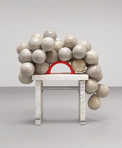 Chair with beige spheres and a red arch on a minimalist gray background.