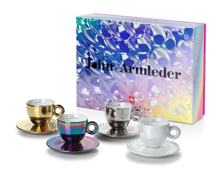 Colorful set of four designer espresso cups with matching saucers, displayed in front of an artistic, vibrant packaging box.