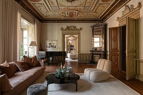 Elegant living room with ornate ceiling, modern furniture, grand piano, and soft lighting creating a cozy atmosphere.