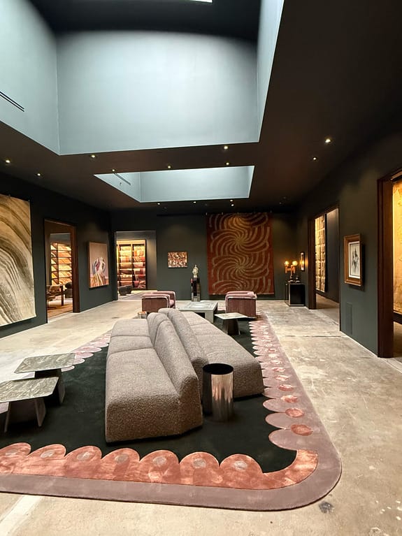 Modern art gallery interior with contemporary furniture, abstract paintings, and skylight illuminating the space.