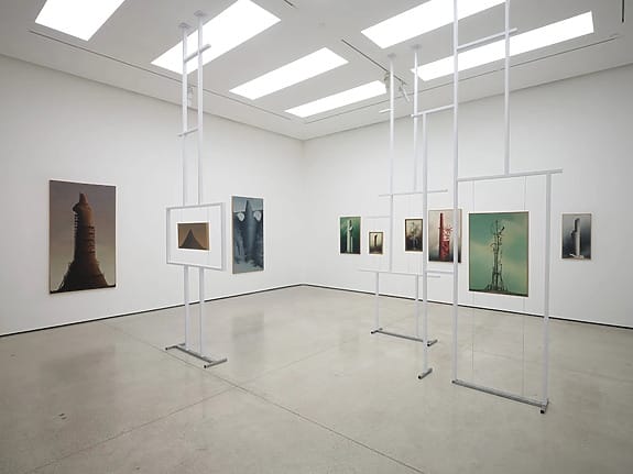 Contemporary art exhibition with abstract paintings and sculptures in a spacious, well-lit gallery room.