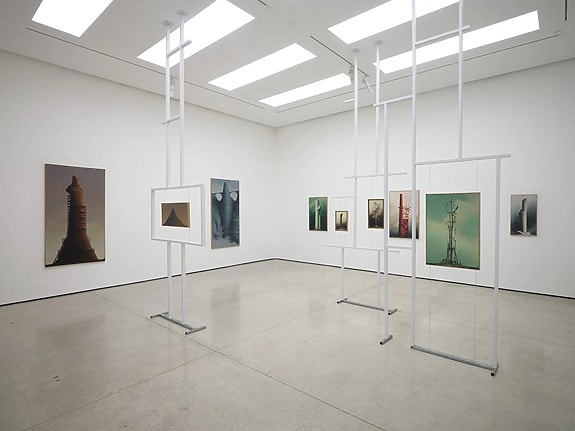 Contemporary art exhibition with abstract paintings and sculptures in a spacious, well-lit gallery room.