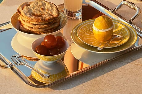 Breakfast tray with pastries, lemon, sweet treats, and juice by the poolside.