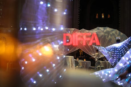 Event venue with glowing DIFFA sign, illuminated decor, and tables set for guests.