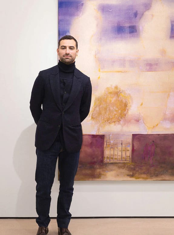 Person standing in front of a purple and yellow abstract painting on a gallery wall.