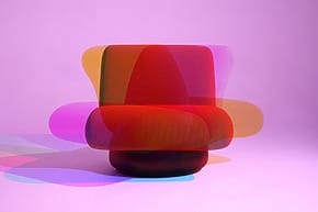 Colorful, abstract chair against a pink background with overlapping translucent shapes in red, orange, and purple hues