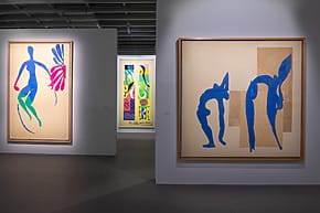 Art gallery at the Grand Palais's Matisse exhibition featuring colorful abstract cutout figures displayed in large frames on white walls.