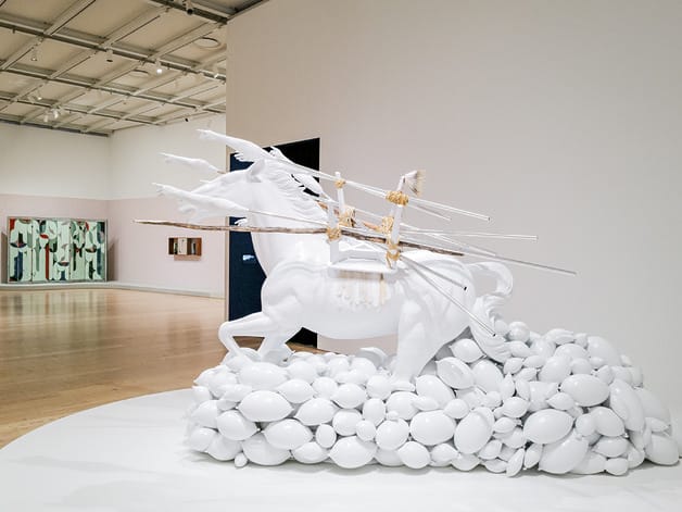 White horse sculpture with arrows and balloons in an art gallery display.