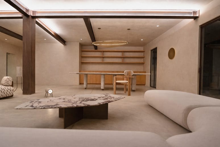 Modern living room with beige sofas, marble coffee table, wooden shelves, and a circular light fixture on the ceiling.