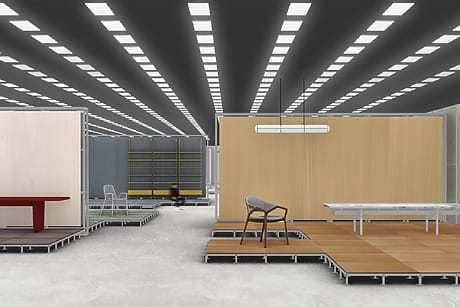 Modern exhibition space with minimalist furniture displays and geometric ceiling lights.