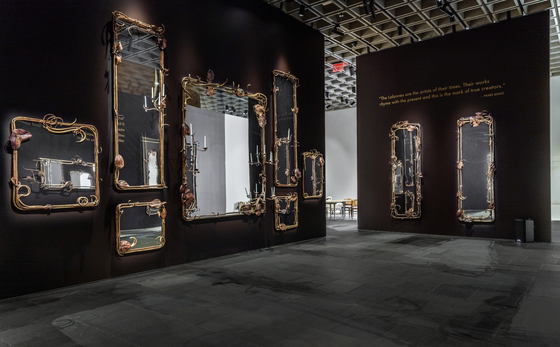 Art installation with ornate mirrors and dark walls in a gallery space with subtle lighting.