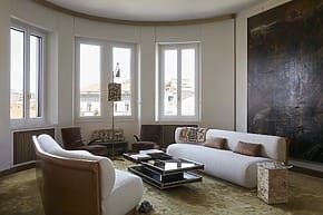 Stylish living room with modern furniture, large windows, neutral tones, and a unique wall painting.