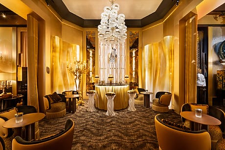 Luxurious, golden-hued lounge with elegant seating, ornate chandelier, and ambient lighting creating a warm, inviting atmosphere.