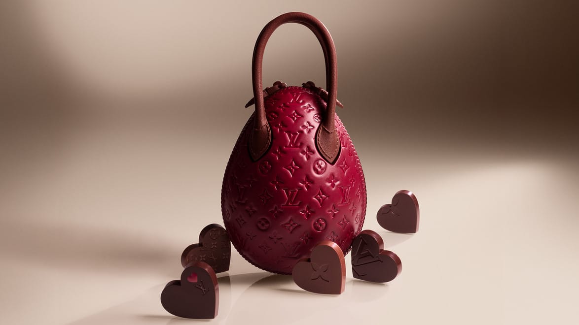 Louis Vuitton elegant egg-shaped chocolate Mother's Day burgundy handbag with an embossed design, designed by Louis Vuitton Pastry Chef Maxime Frédéric in tribute to Nicholas Ghesquire, surrounded by heart-shaped chocolates on a neutral background.