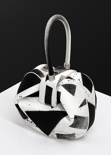 Black and white abstract handbag on a white surface with a black background.