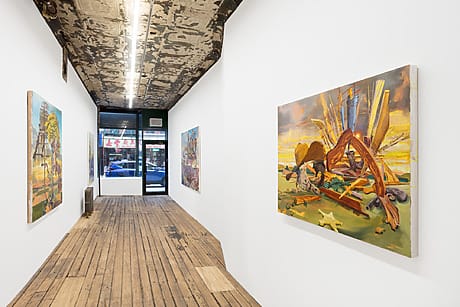 Art gallery with wooden floors and white walls displaying colorful paintings in a contemporary setting.