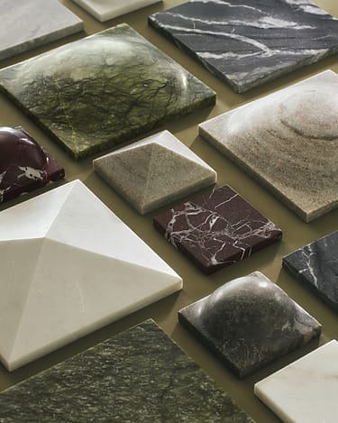 Assorted stone and marble slab samples in various colors and textures displayed on a neutral background.
