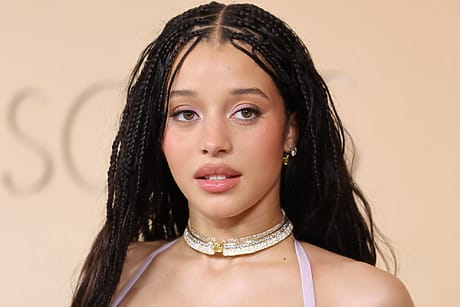 Actress Chase Infiniti on the red carpet with braided hair wearing a choker necklace and a sleeveless top against a neutral background.