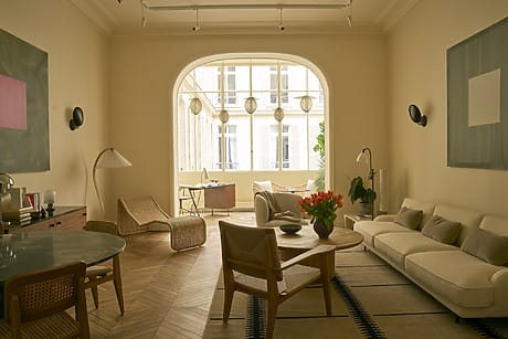 Modern living room with beige furniture, wooden flooring, and large window letting in natural light.
