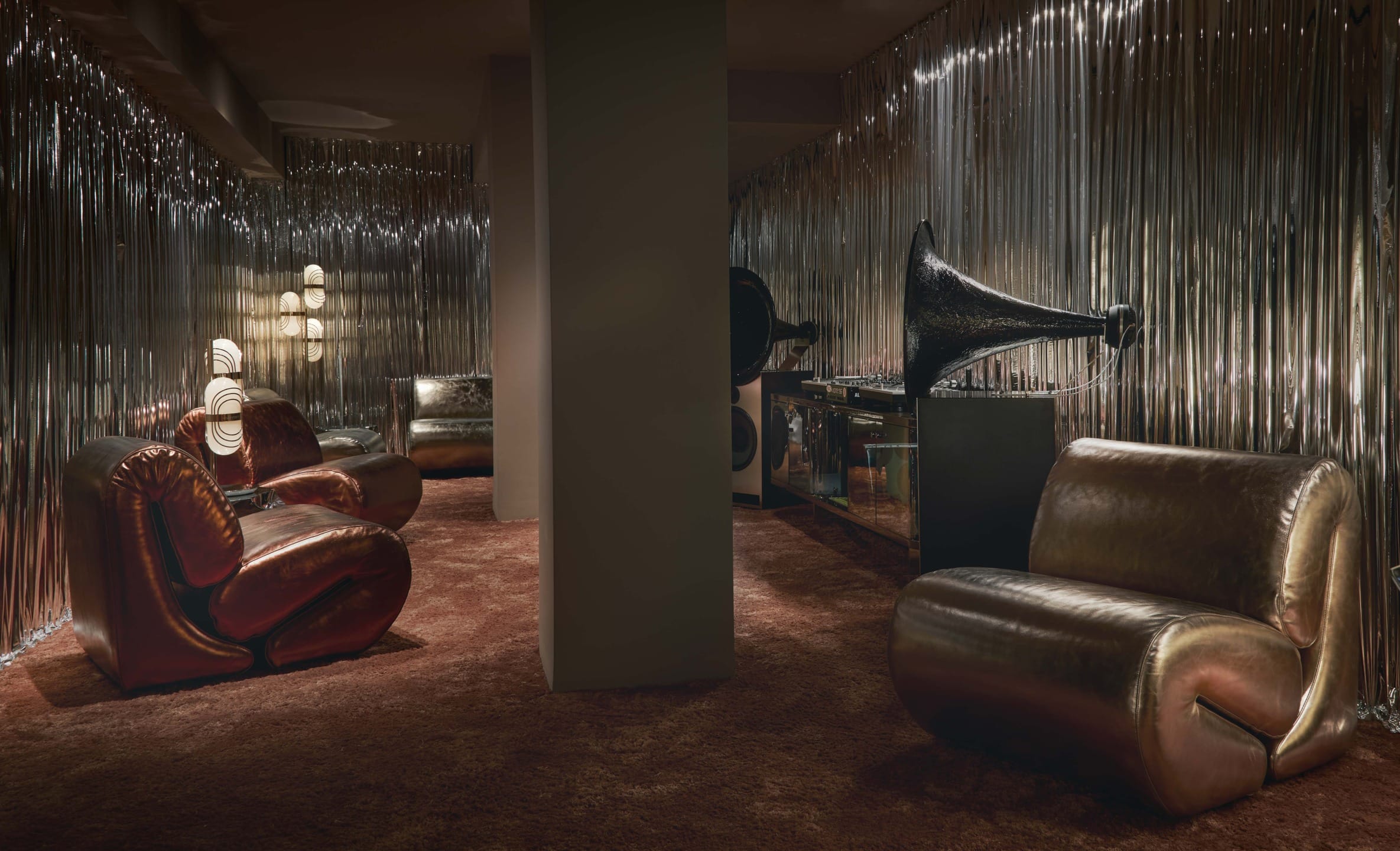 Stylish retro lounge with plush chairs, gramophone, and metallic walls creating a vintage atmosphere.