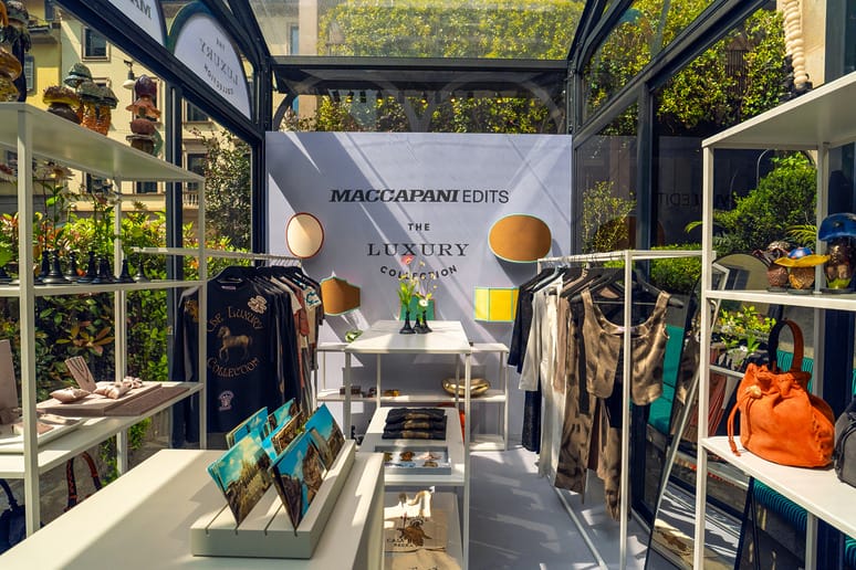 Luxury clothing and accessories display in a bright and modern glass boutique setting.