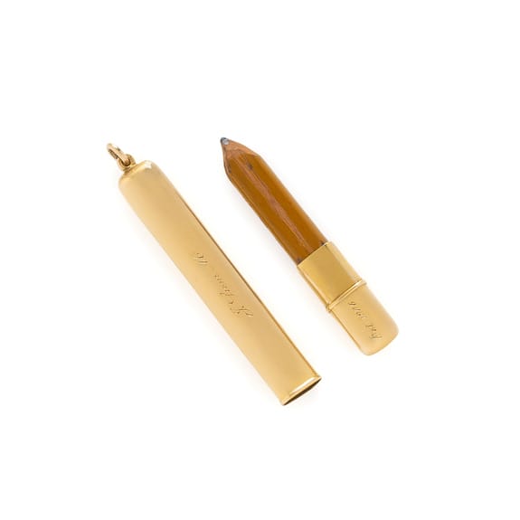 Gold-colored pencil salvaged from the TItanic, with a detachable cap lying beside it.