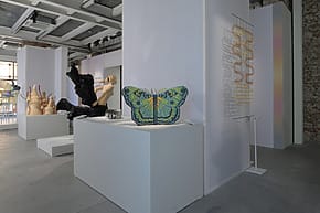 Art exhibition featuring sculpture and textile works, including a large butterfly piece displayed in a modern gallery space.