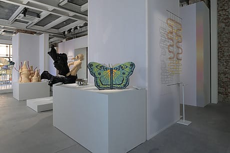 Art exhibition featuring sculpture and textile works, including a large butterfly piece displayed in a modern gallery space.