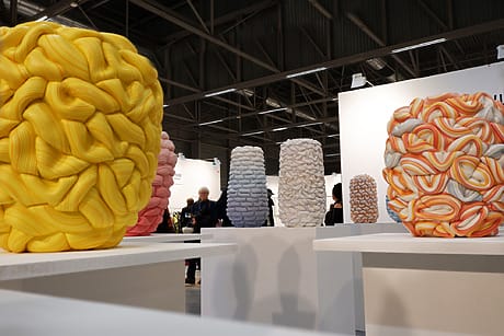 Colorful abstract sculptures on display in an art gallery with visitors in the background.