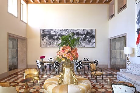 Luxurious hotel lobby with elegant seating, large floral centerpiece, abstract art, and checkerboard flooring.