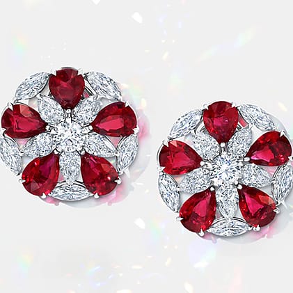 Silver earrings with red and clear gemstones arranged in a floral pattern.