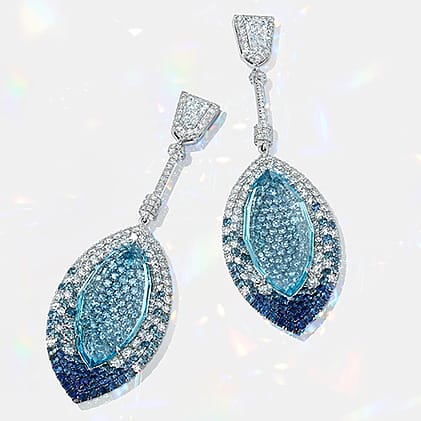 Elegant blue and silver drop earrings encrusted with sparkling gemstones on a light background.