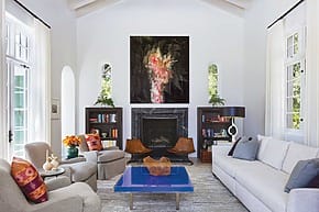 Spacious living room with stylish furniture, large abstract painting above fireplace, and modern decor elements.