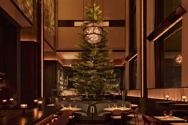 Elegant restaurant interior with a large indoor tree, warm lighting, and tables set for dining.