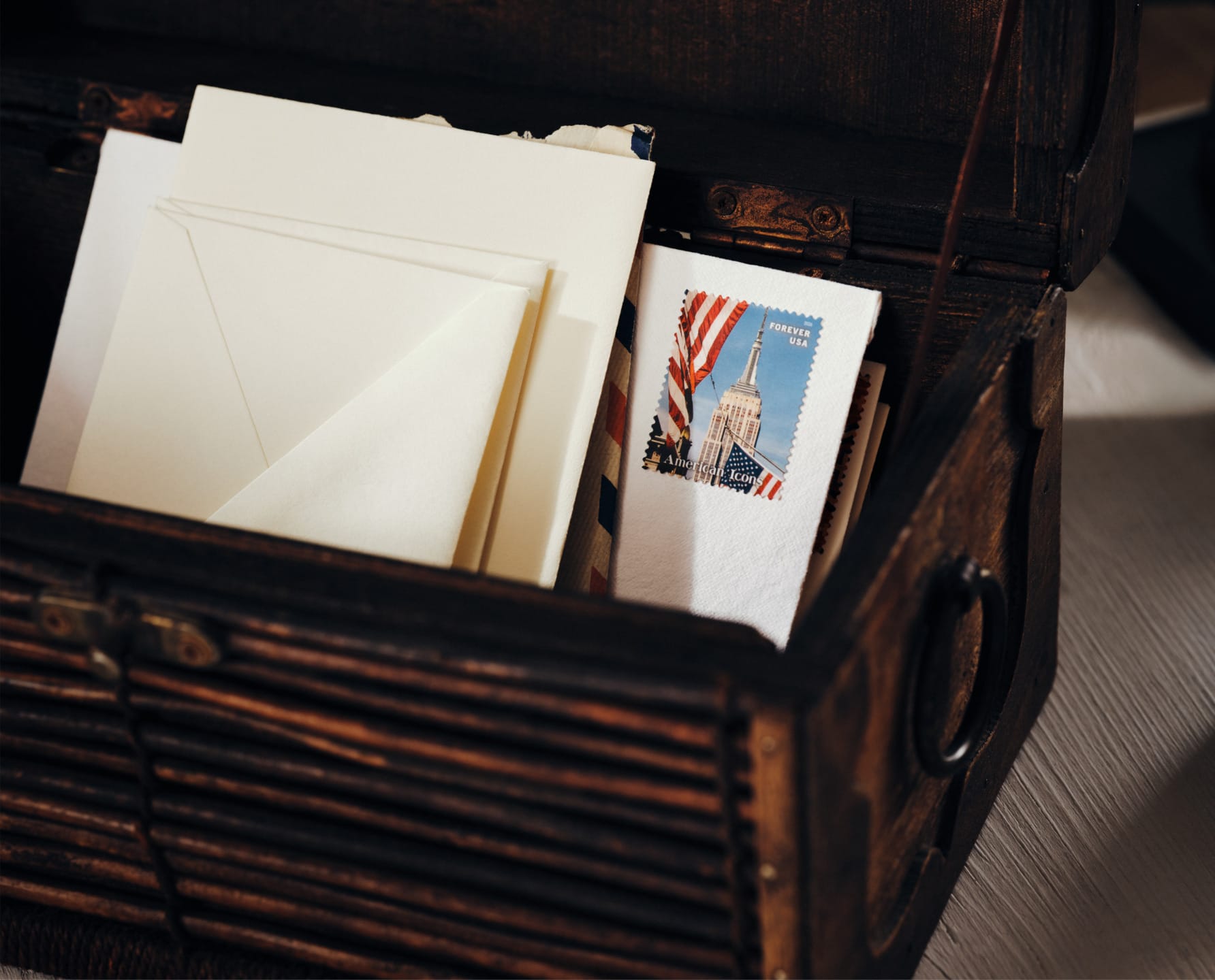 Wooden box with envelopes, one showing a postage stamp featuring a white building with flags and a clear blue sky background.