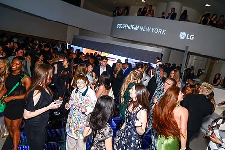 A lively crowd enjoys an event at the Guggenheim Museum in New York, featuring a vibrant lighted floor and socializing guests.