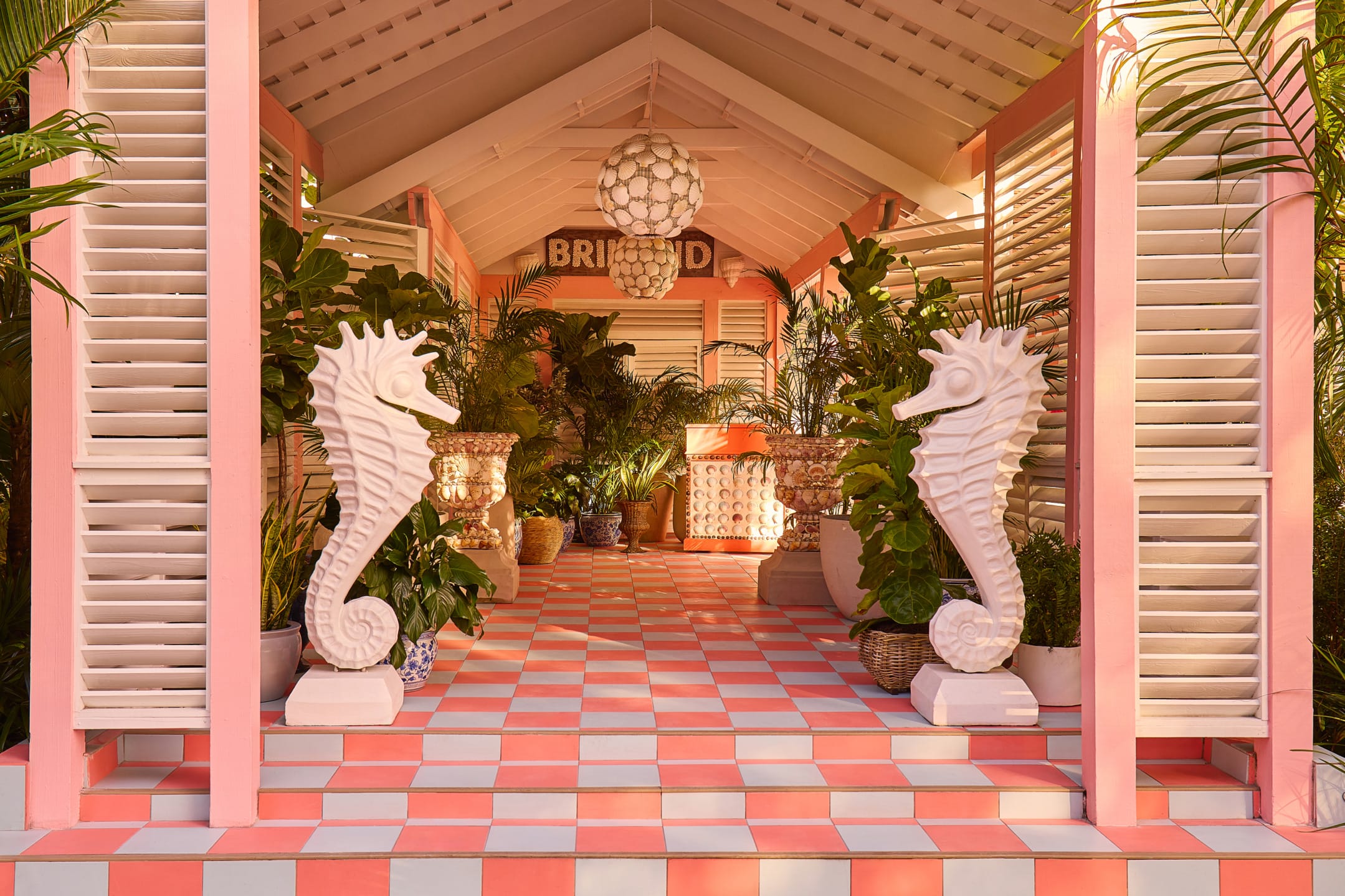 Tropical-themed patio with large seahorse sculptures, pink and white checkered floor, lush plants, and wooden lattice walls.