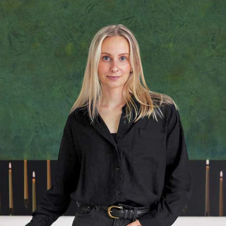 Person wearing black shirt stands in front of a large green and black abstract painting.
