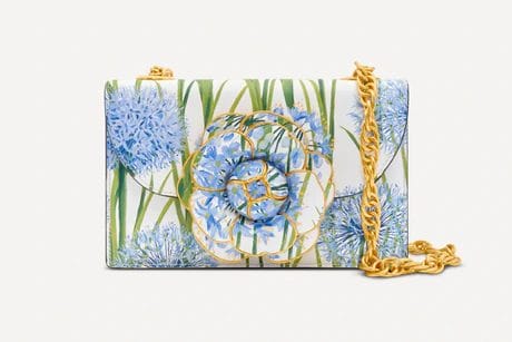 White and green floral handbag with blue flower design and gold chain strap.